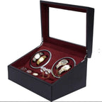 Black jewelry watch winder box with red interior containing luxury watches and jewelry on a white background
