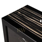 Close-up of a black and white striped surface with a clear glass panel of a luxury watch winder