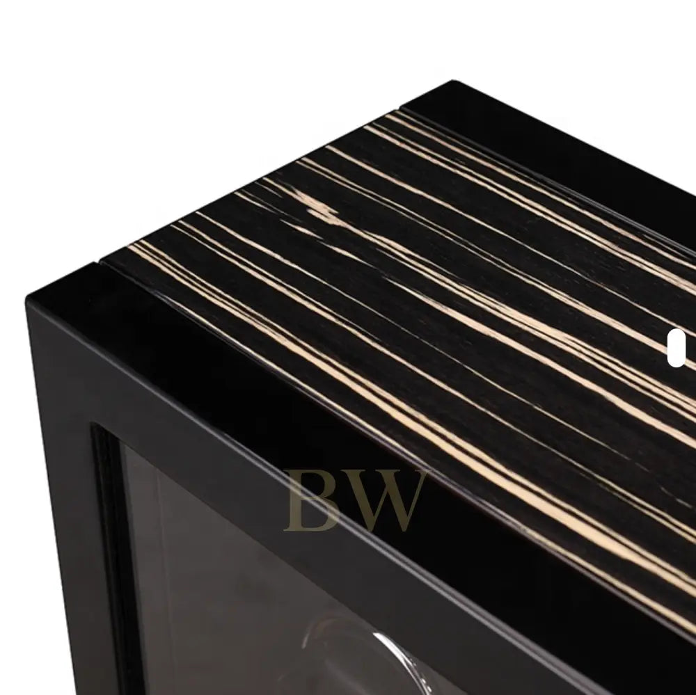 Close-up of a black and white striped surface with a clear glass panel of a luxury watch winder