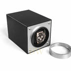Black Rolex inside a carbon watch winder with a silver cover on a white background