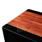 Wooden surface of watch winder with black trim on a white background
