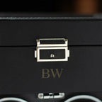 Close-up of a black leather suitcase with a gold clasp.