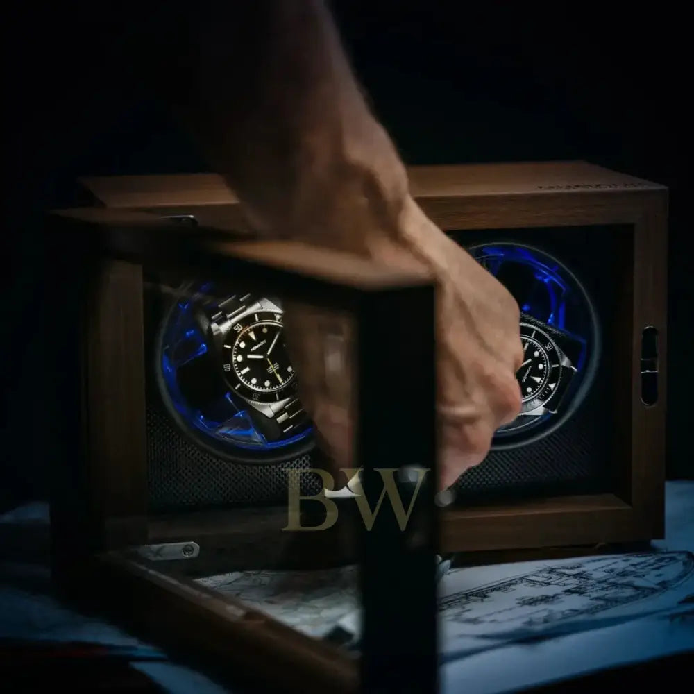 Hand opening a wooden watch winder box containing two watches with blue accents
