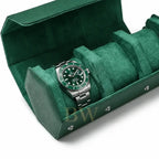 A green and silver Rolex Submariner Hulk watch displayed inside an open green velvet watch roll on a white background.