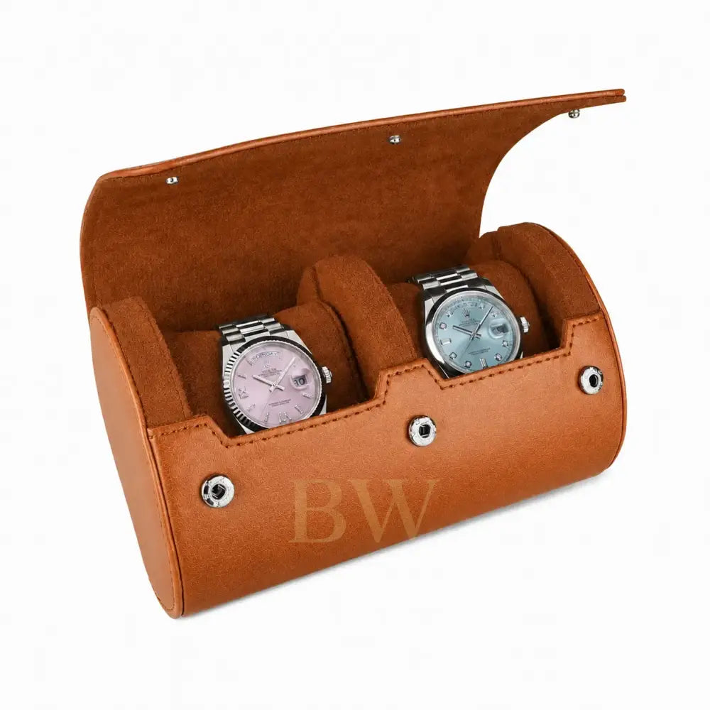A brown leather watch roll with an open lid, featuring two cushioned compartments holding two Rolex watches, photographed on a clean white background.