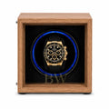 Rolex Daytona watch in a black watch winder case within a wooden box on a white background