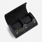 A black cylindrical watch roll case with an open hinged lid, featuring a velvet-lined interior and silver-tone metal rivets, shown on a light gray background.