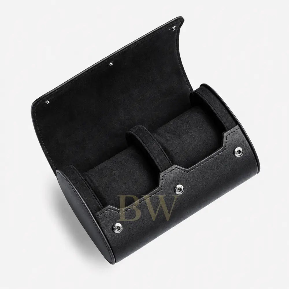 A black cylindrical watch roll case with an open hinged lid, featuring a velvet-lined interior and silver-tone metal rivets, shown on a light gray background.