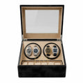 A luxury watch winder box with a black textured exterior and a beige interior, shown open with two watch rotation slots containing two watches. The top lid features a clear glass window, and the bottom section has individual watch slots.