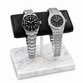 Two silver luxury watches Tudor and Audemars Piguet on a marble watch stand with a white background